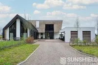 Maison moderne avec toit en pente, garage attenant, allée gravillonnée et jardin verdoyant. Idéale pour le confort contemporain.