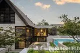 Maison moderne avec véranda, piscine et jardin verdoyant, entourée de paysages naturels à la tombée du jour.