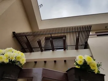 Vue d’un auvent moderne avec des fleurs jaunes en pot, sous un ciel nuageux. Décor extérieur élégant et accueillant.